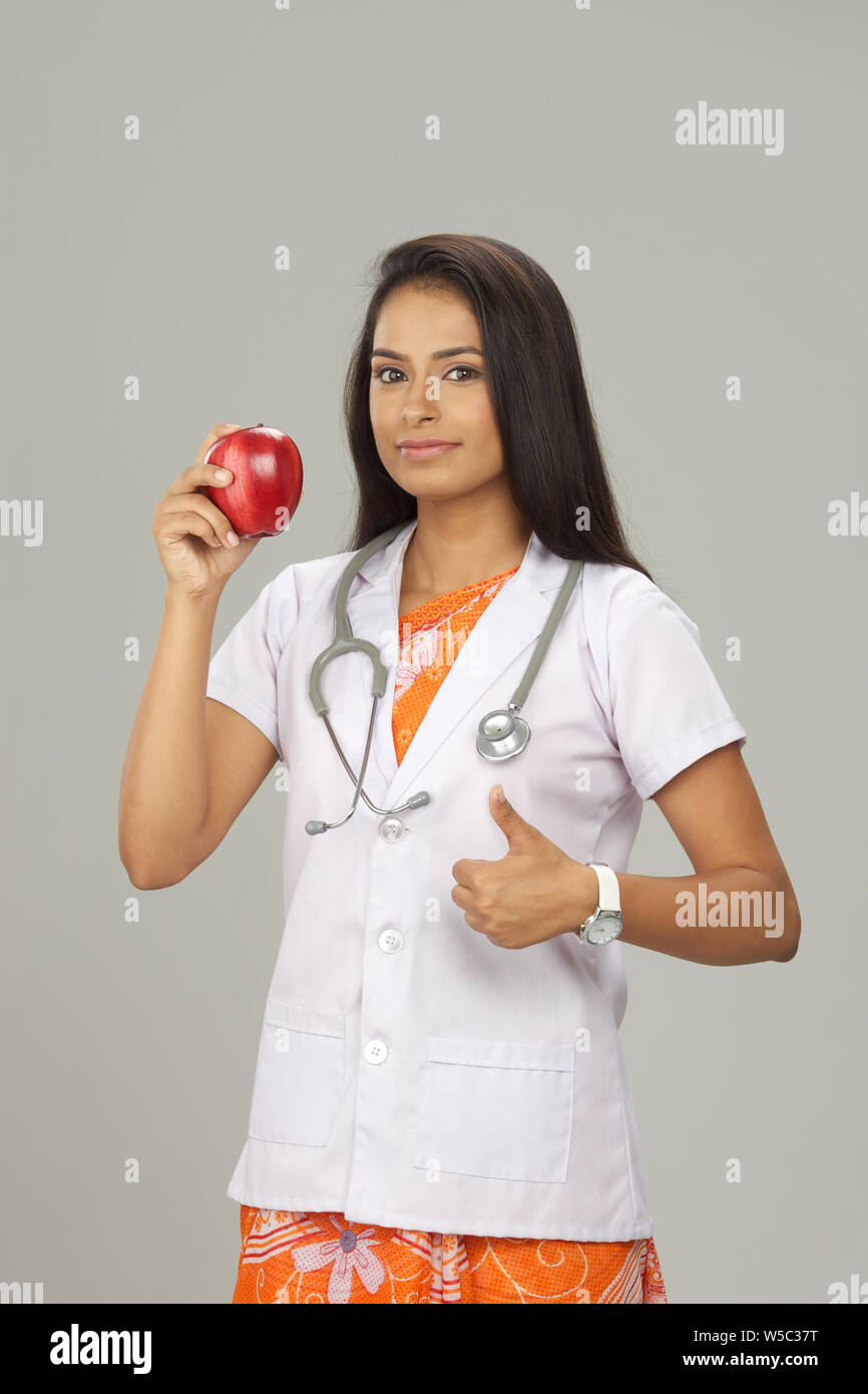 Female doctor showing an apple and thumb up sign Stock Photo - Alamy