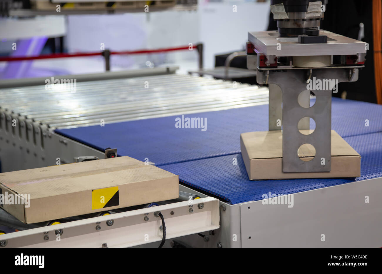 Robot arm loading carton on conveyor in manufacturing production line ...