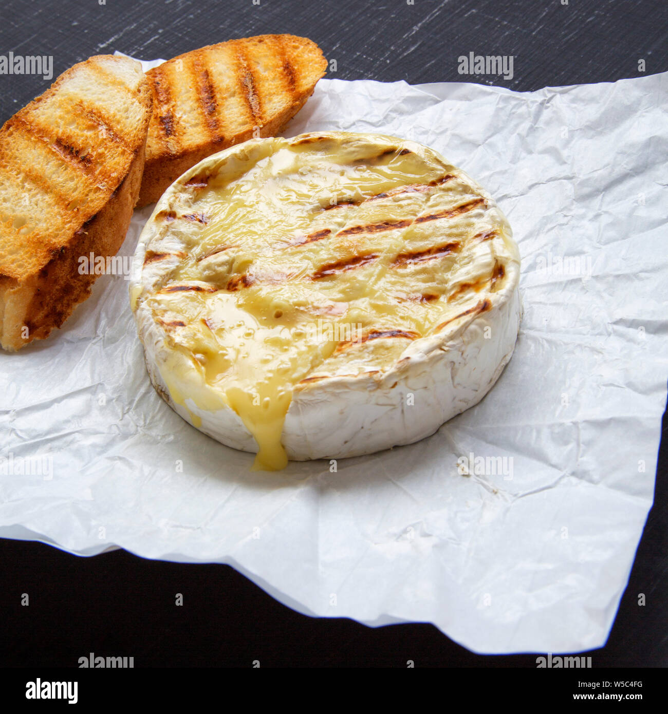 Grilled camembert cheese on a black surface, side view. Close-up Stock  Photo - Alamy