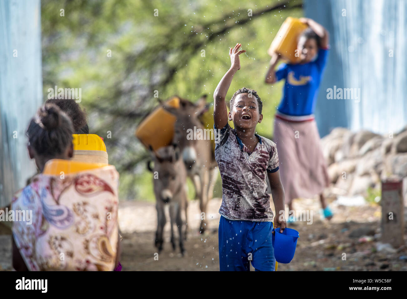 A young boy throws water into the air as he strolls happily down a