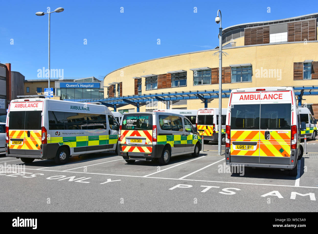 Back view of various patient delivery healthcare ambulances parked outside main entrance NHS Queens Hospital  Romford Havering East London England UK Stock Photo