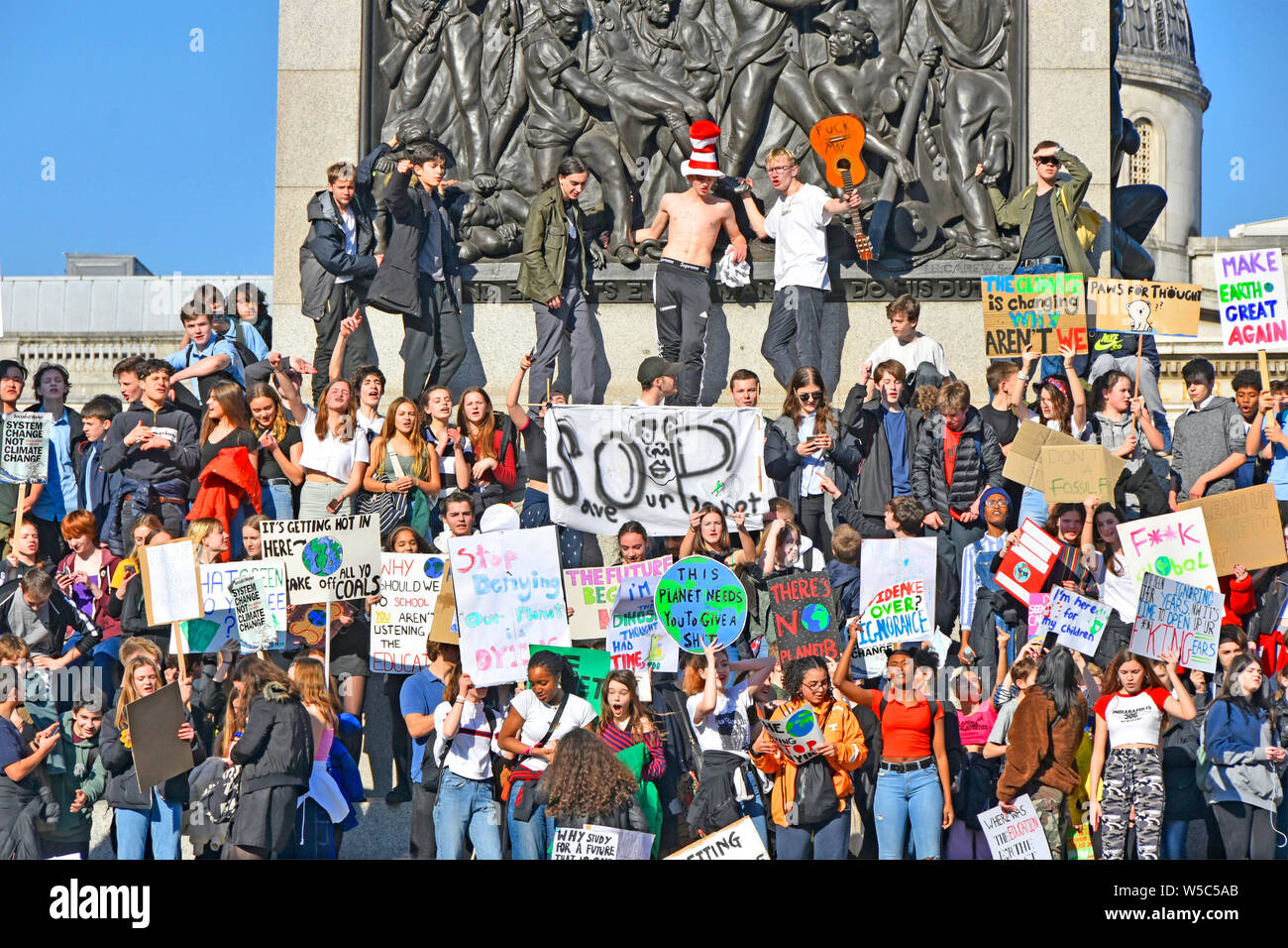 Group of teenagers school children kids miss school to strike & protest on climate change waving placard & chanting Trafalgar Square London England UK Stock Photo