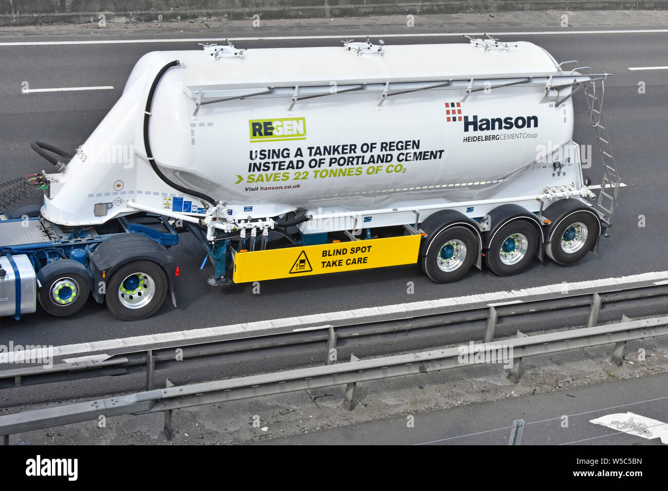 Advertising on Hanson Heidelbergcement business group bulk tanker trailer promoting Regen alternative to Portland Cement saves CO2 seen on UK motorway Stock Photo