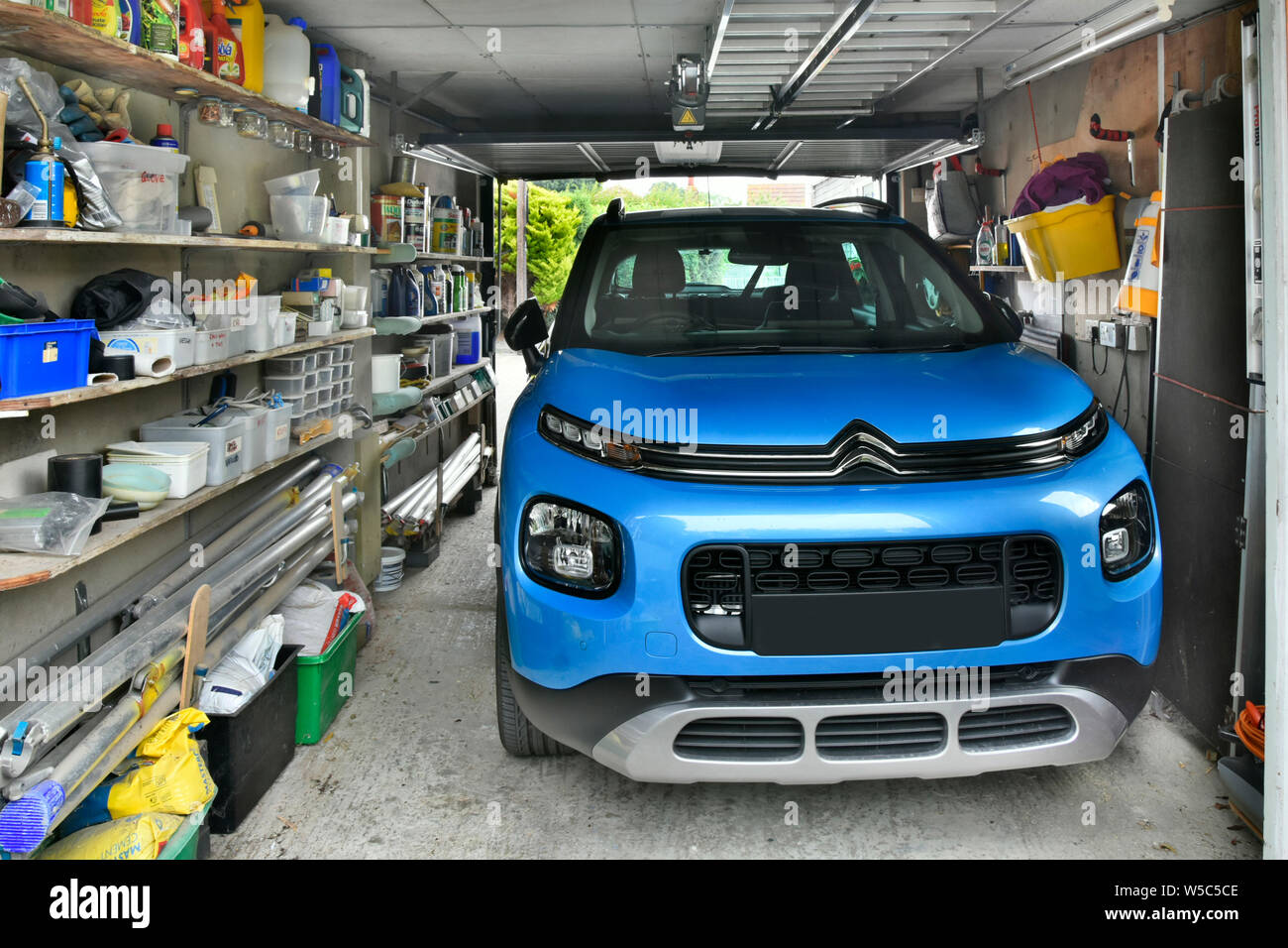 Citroen Aircross car parked in attached to house residential property garage  shelving for storage sundry household paraphernalia & tools  England UK Stock Photo