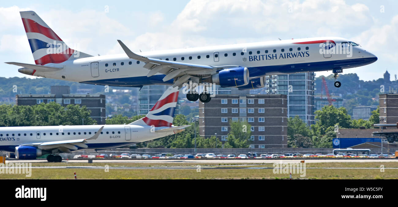 Side view British Airways airplane landing London City Airport BA plane taxiing ready for taking off housing beyond Silvertown Newham East London UK Stock Photo