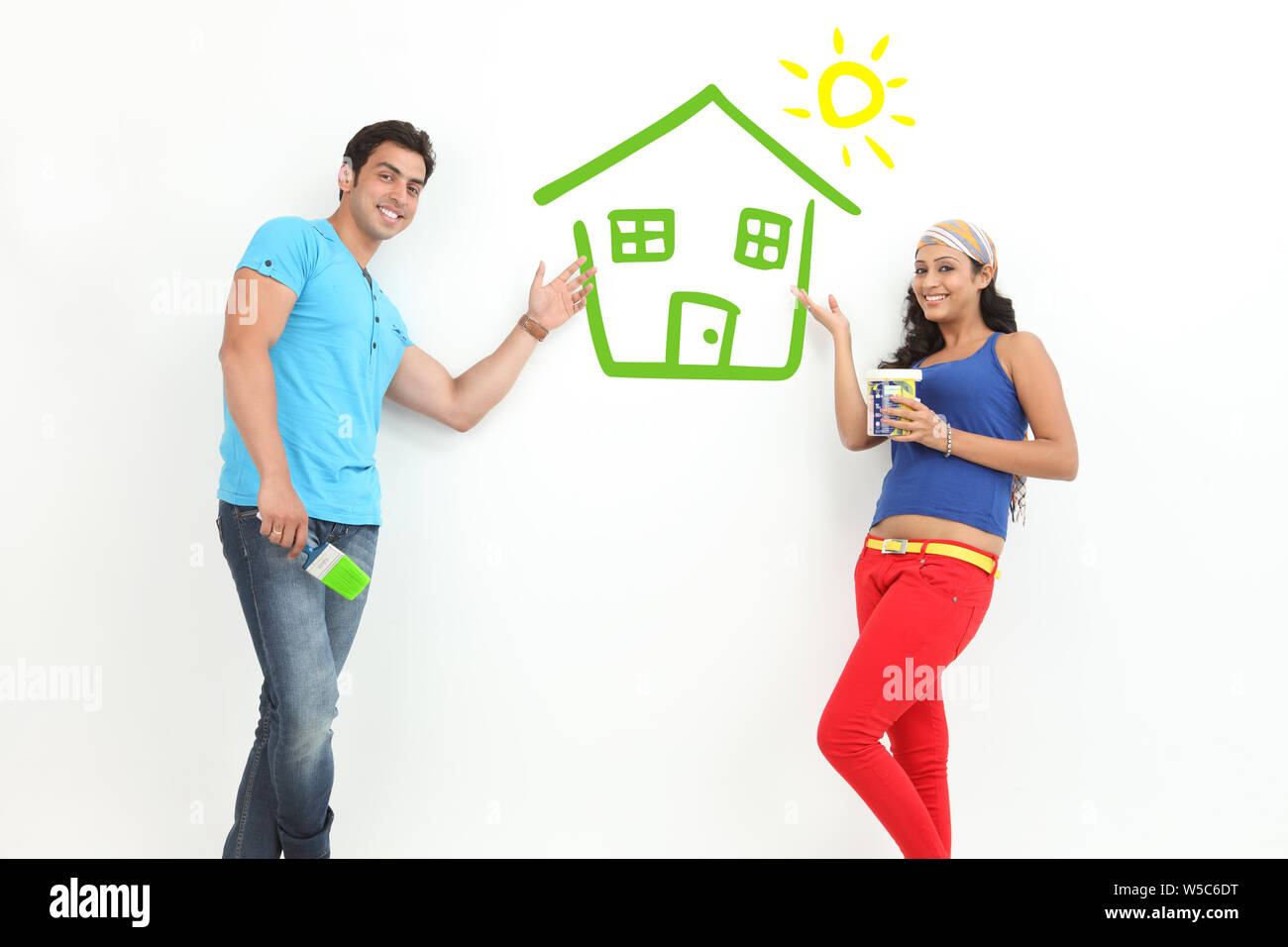 Couple with eco friendly house painted on wall Stock Photo