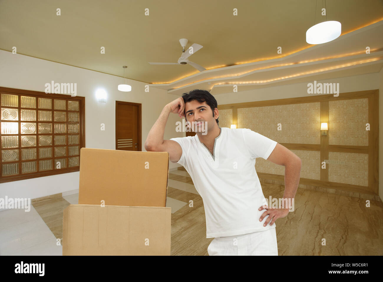 Man moving boxes into new home and day dreaming Stock Photo