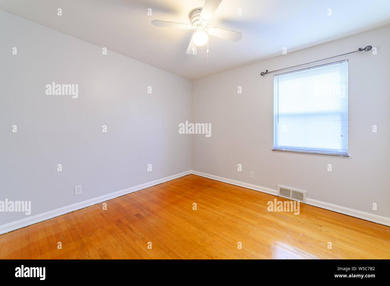 A Small Undecorated Bedroom With Wood Floors Stock Photo