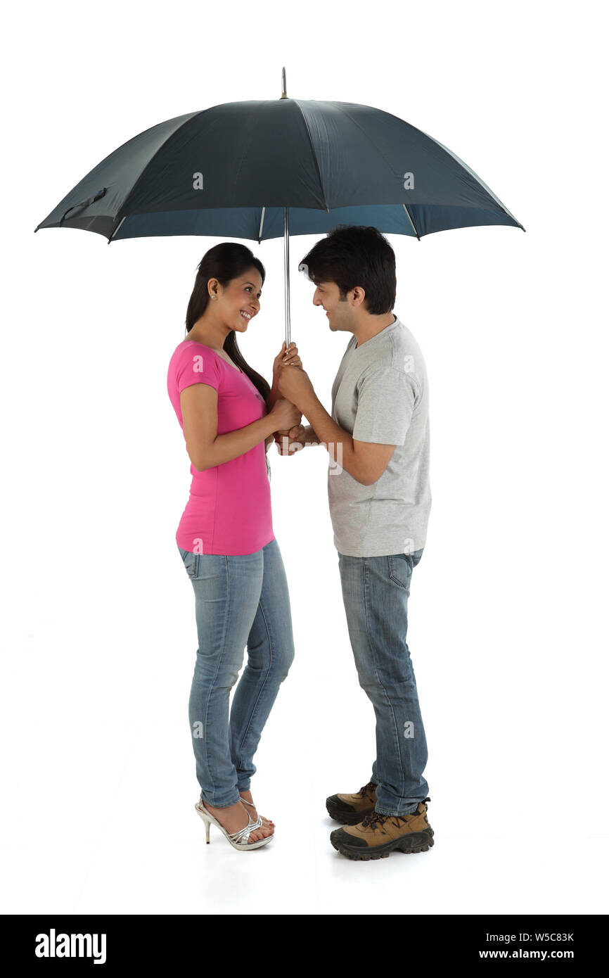 Man with his wife standing under an umbrella and smiling Stock Photo