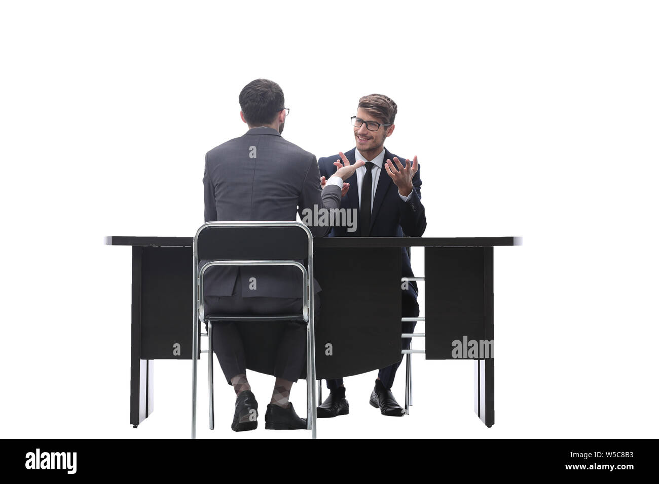 two businessmen talking, sitting at his Desk Stock Photo