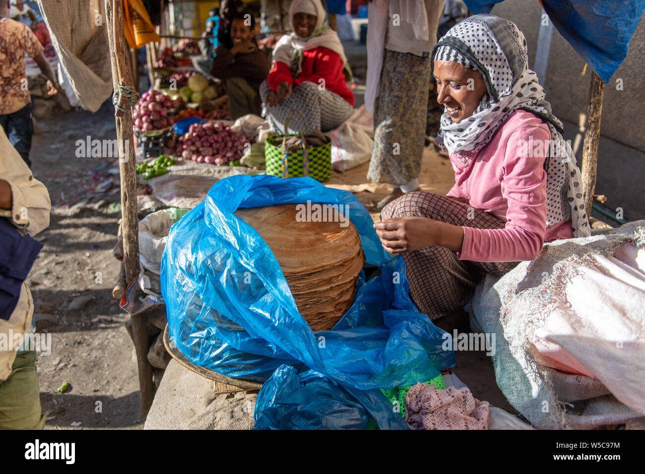 Woman smiling as she prepares Injera or Ethiopian flatbread at outdoor market, Deber Berhan, Ethiopia Stock Photo