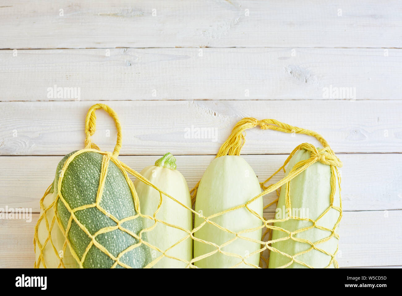 Top view of fresh courgettes in row bag over white rustic background ...