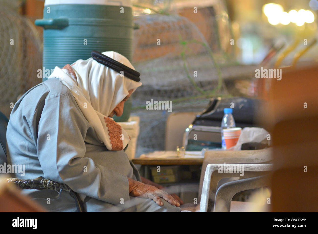 DOHA, QATAR - FEBRUARY 27, 2016: An old qatari man felt asleep, sitting at a table of a cafe in Souq Wakif. Taken at night with no flash. Stock Photo