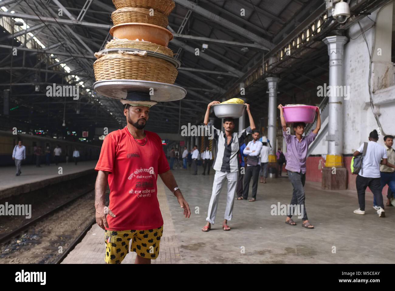 Porters at Chhatrapati Shivaji Maharaj Terminus (CSMT) in Mumbai, India, carrying baskets with fish on their heads to deliver to an incoming train Stock Photo