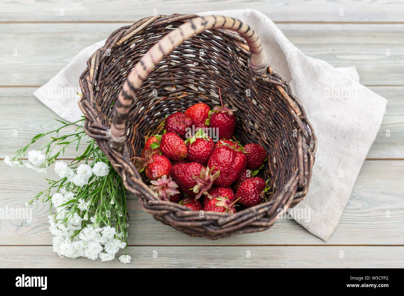 Ripe strawberries in a basket. Summer food composition on a wooden table. Stock Photo