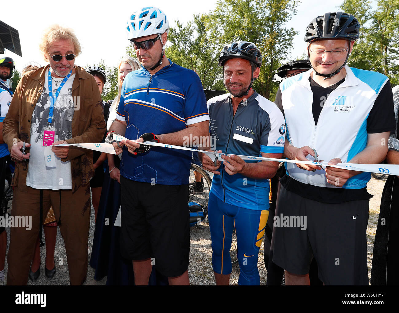Bad Staffelstein, Germany. 28th July, 2019. Entertainer Thomas Gottschalk (l-r), Markus Söder (CSU), Minister President of the Free State of Bavaria, Thorsten Glauber (Free Voters), State Minister for the Environment and Consumer Protection, and Hans Reichhart (CSU), State Minister for Housing, Construction and Transport, cut a ribbon at the opening of the 30th BR-Radltour. Credit: Peter Kolb/dpa/Alamy Live News Stock Photo