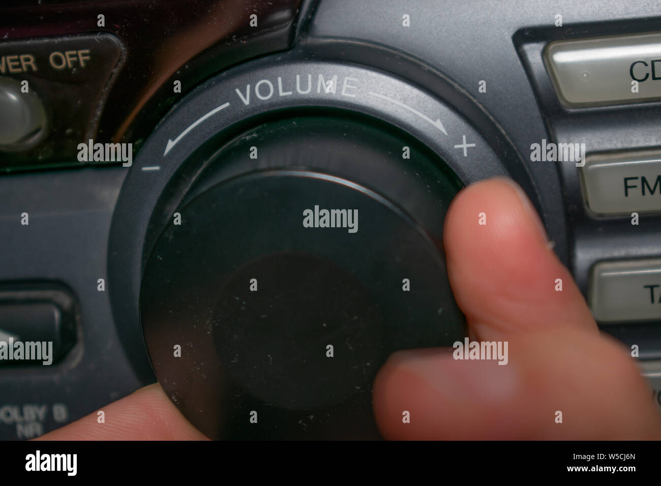 A person turning the volume wheel up or down (the focus is on the word