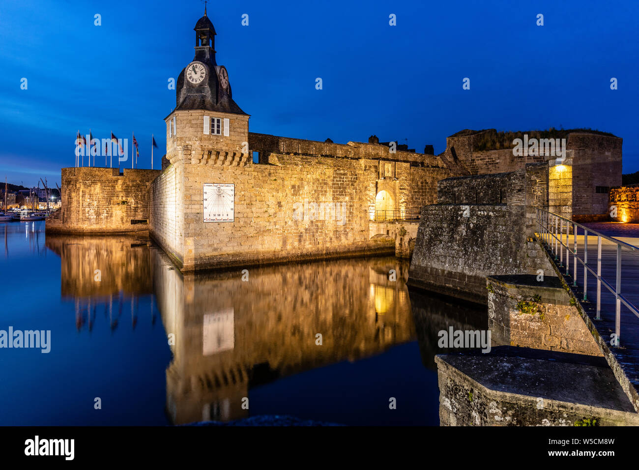 Night Time, the clock tower and short causeway entrance to the old fortified town of Concarneau Stock Photo