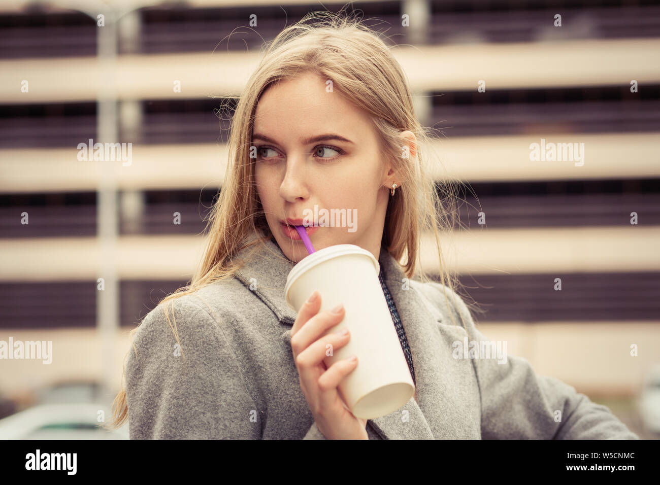 serious blond young woman in street cafe drinks cocktail looking aside Stock Photo