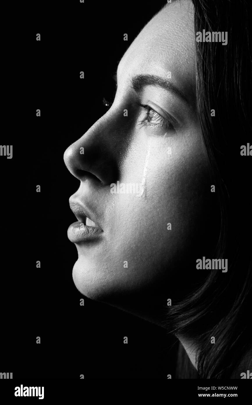 sad woman crying, looking aside on black background, closeup portrait, profile view, monochrome Stock Photo