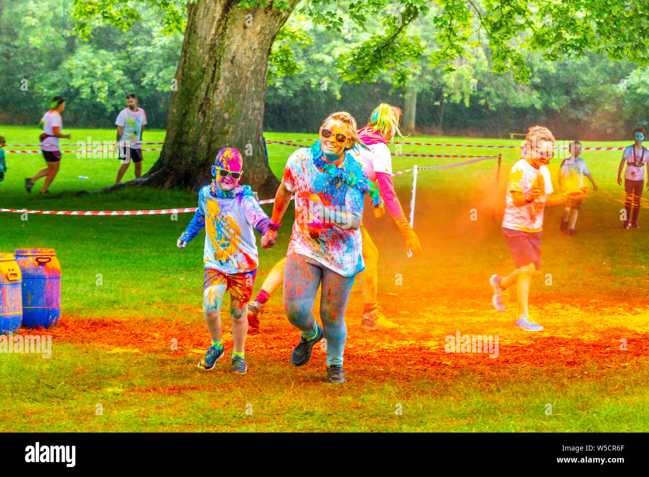 Northampton, UK. 28th July 2019. Fun Colour Rush in Abington Park, a family event with over 1500 taking part in the rain out of the people entered, raising money for 3 different charities, six waves going off in 15 minuets intervals, a wet morning but people still having a fun time. Credit: Keith J Smith./Alamy Live Stock Photo