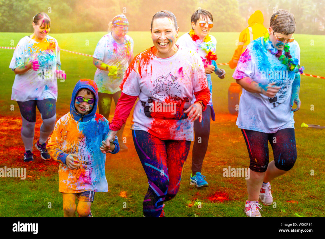 Northampton, UK. 28th July 2019. Fun Colour Rush in Abington Park, a family event with over 1500 taking part in the rain out of the people entered, raising money for 3 different charities, six waves going off in 15 minuets intervals, a wet morning but people still having a fun time. Credit: Keith J Smith./Alamy Live Stock Photo