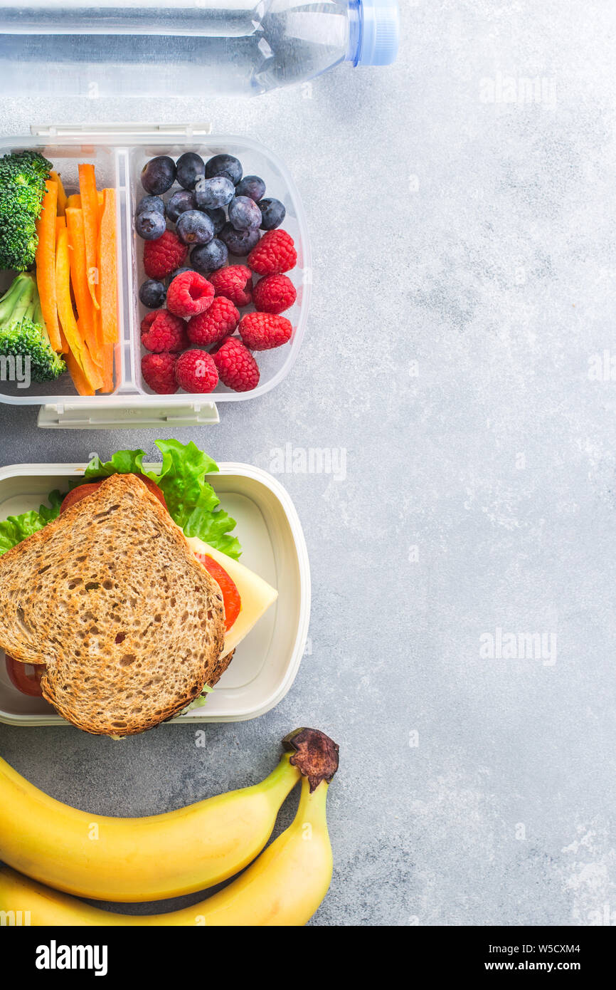 School lunch box with sandwich vegetables water almonds and fruits on