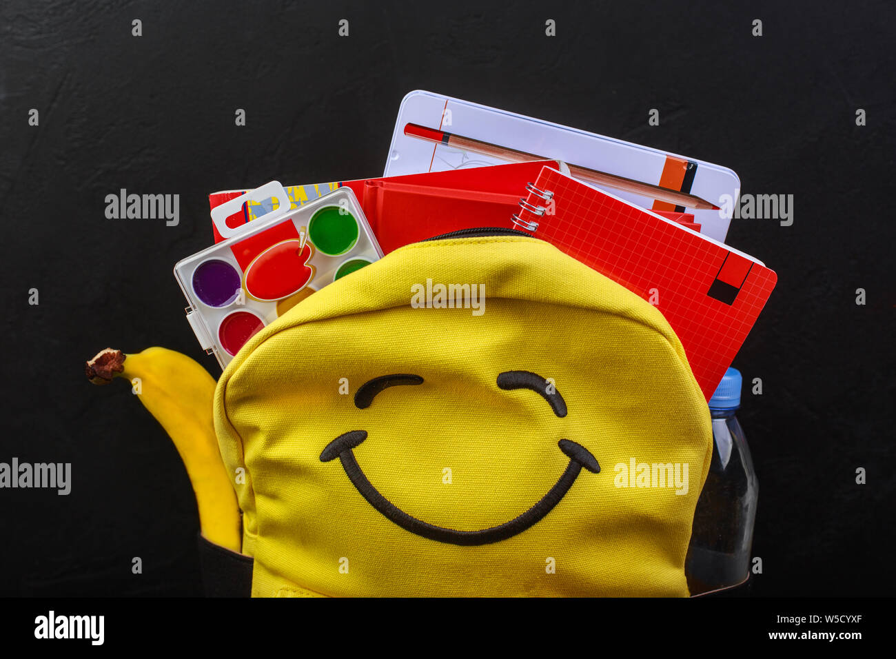 Yellow school backpack with accessories on black background Stock Photo