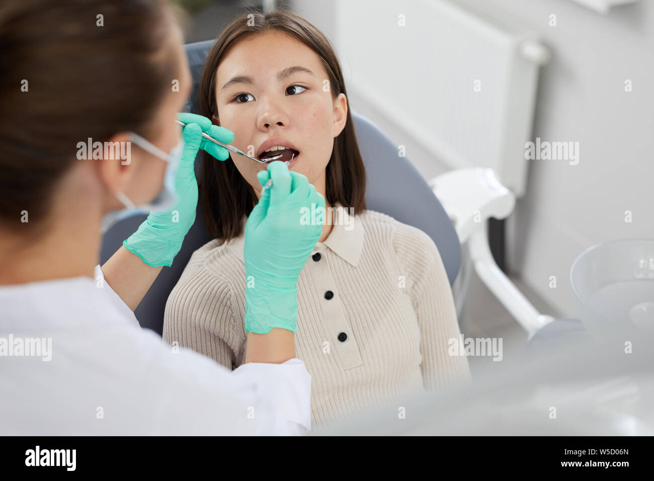 High angle portrait of Asian girl lying in dental chair with female dentist examining teeth, copy space Stock Photo