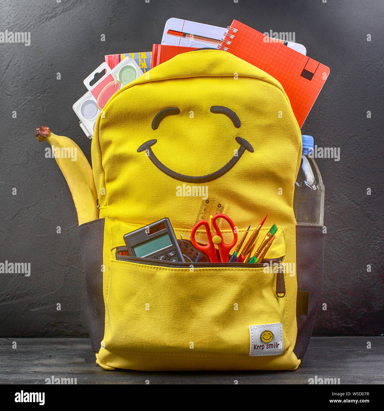 Yellow school backpack with accessories on black background Stock Photo