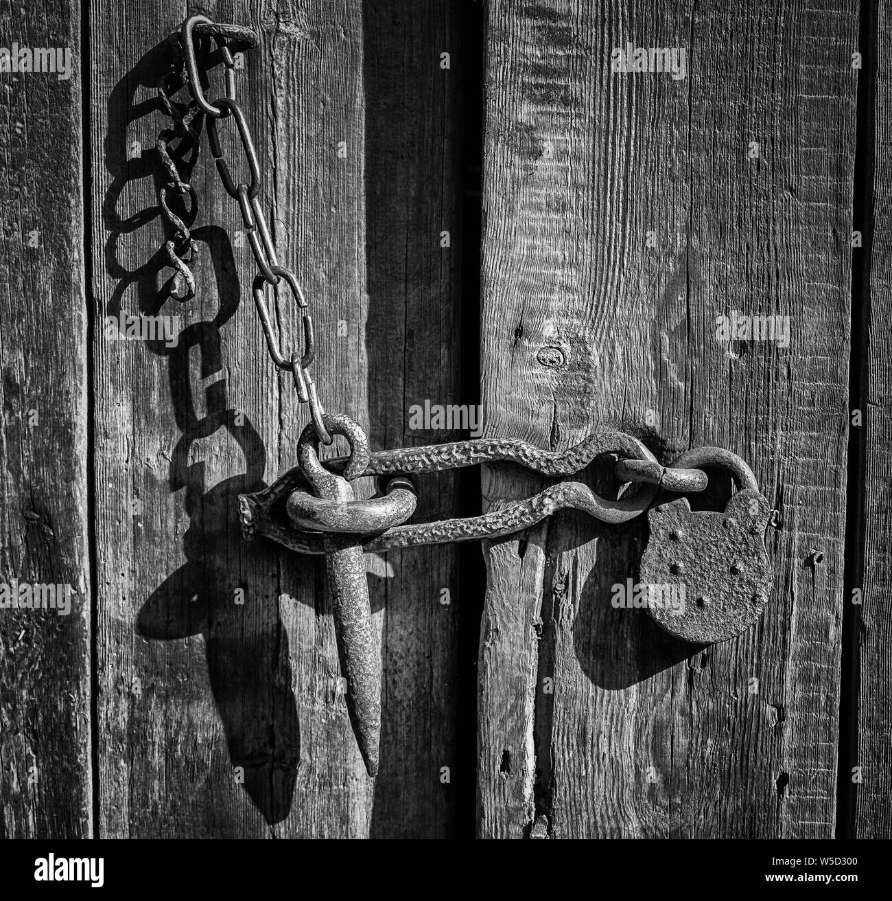 Forged, rusty hasp and padlock on a rustic barn door Stock Photo