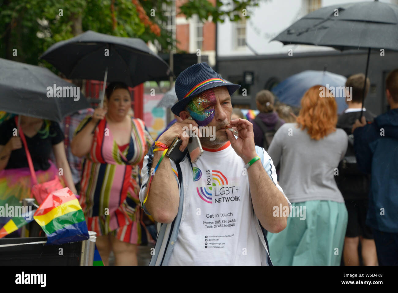 Spiv guy, with cigarette & two phones at Pride event in Nottingham Stock Photo