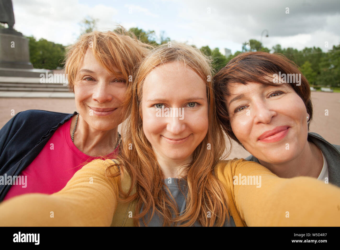 Three diverse happy women friends making selfie photo and having fun outdoors Stock Photo