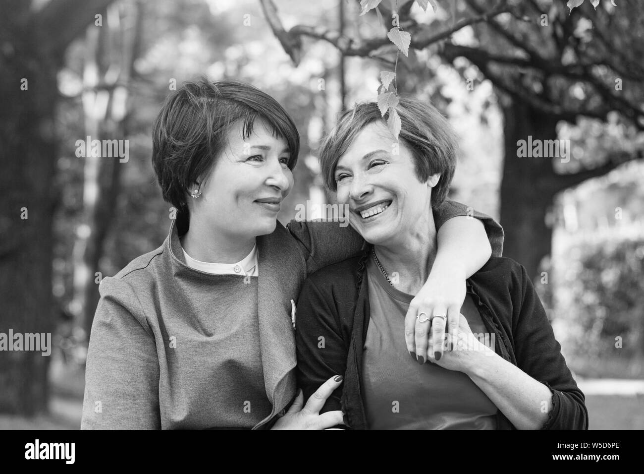 Happy women cuddling, walking in park and resting, lifestyle black and white portrait Stock Photo