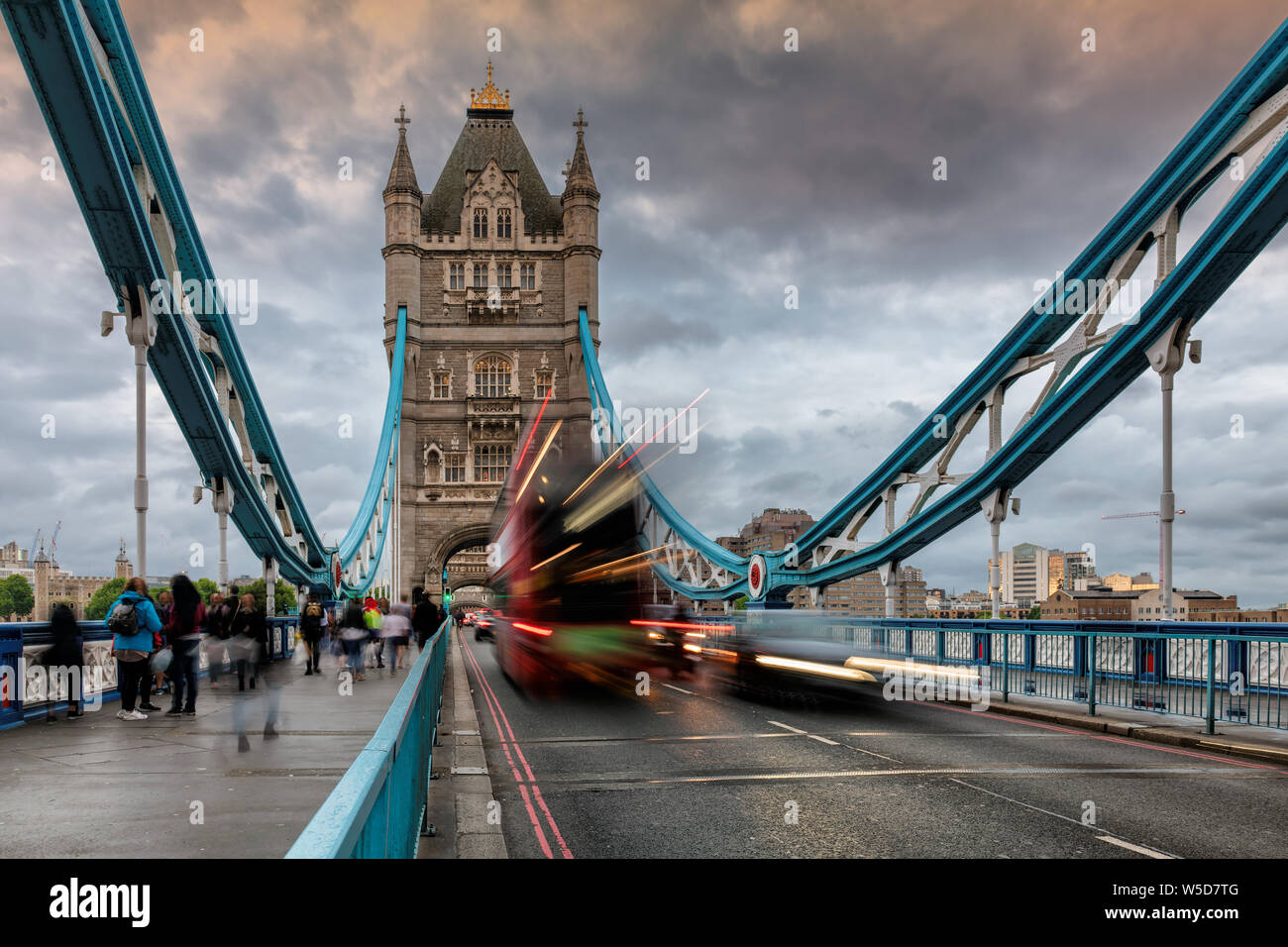 Tower Bridge in London, UK in evening with moving red double-decker bus leaving light traces, United Kingdom. Stock Photo