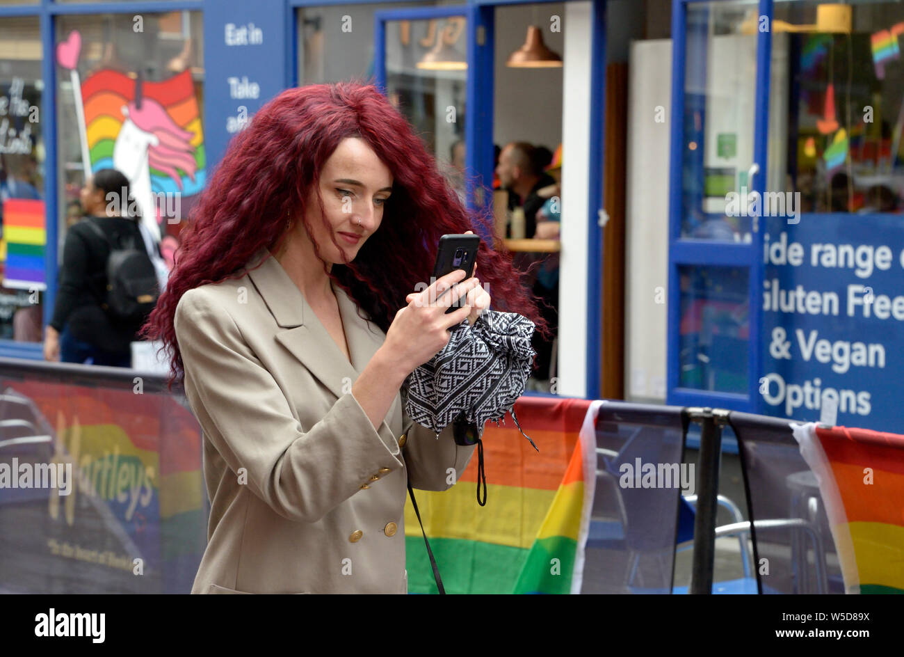 Lady with red hair, taking photographs at Pride, Nottingham. Stock Photo