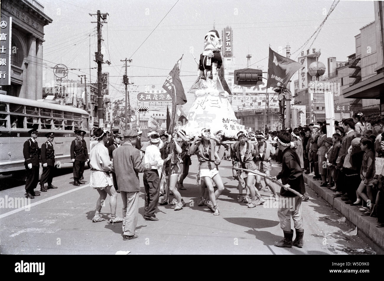 [ 1960s Japan - Effigy of Nobusuke Kishi ] —   Japanese men in happi coats are carrying an effigy of Prime Minister Nobusuke Kishi (岸信介, 1896–1987) on a Tokyo street during a demonstration against the Treaty of Mutual Cooperation and Security between the United States and Japan (安保条約), 1960 (Showa 35). Stock Photo