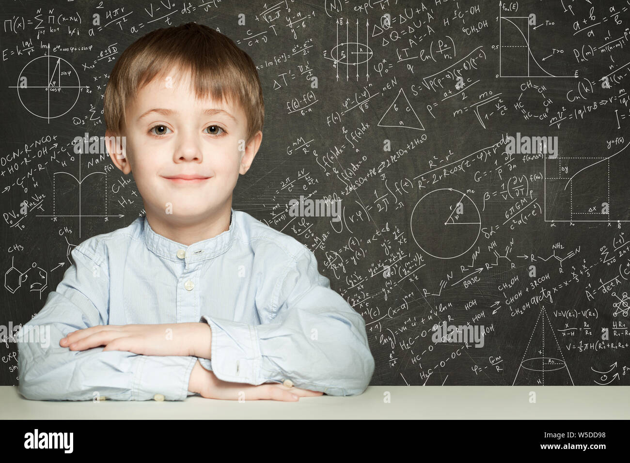 Cute smart child student on blackboard background with science formulas