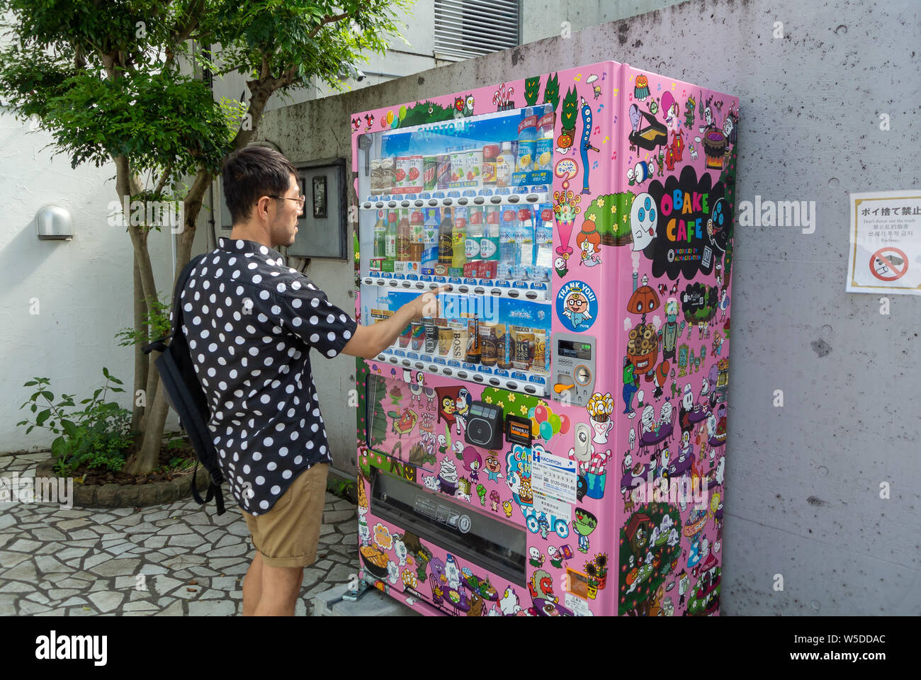 An asian tourist buying a drink from a colorful vending machine, Omotesando, tokyo, japan, 20192019 Stock Photo