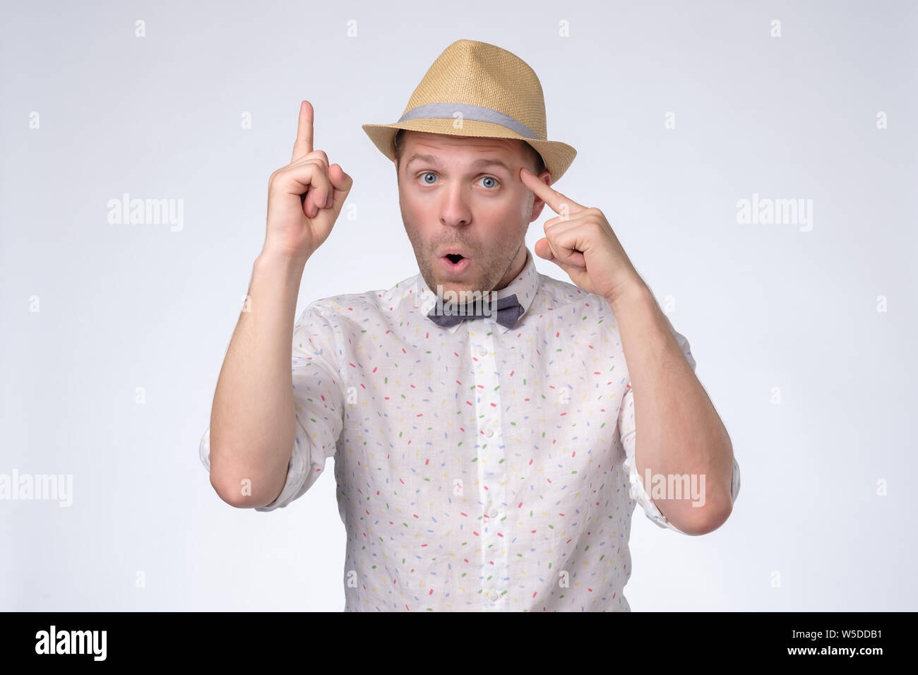 Tourist man in summer hat has excited expression, index finger up, recieve good idea Stock Photo