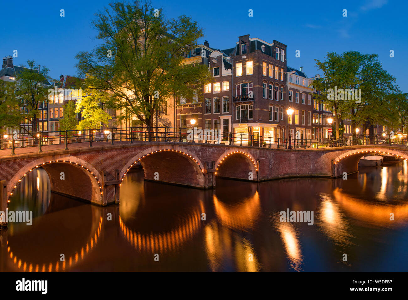 Reflection of bridge along the canal at night in Amsterdam, Netherlands Stock Photo