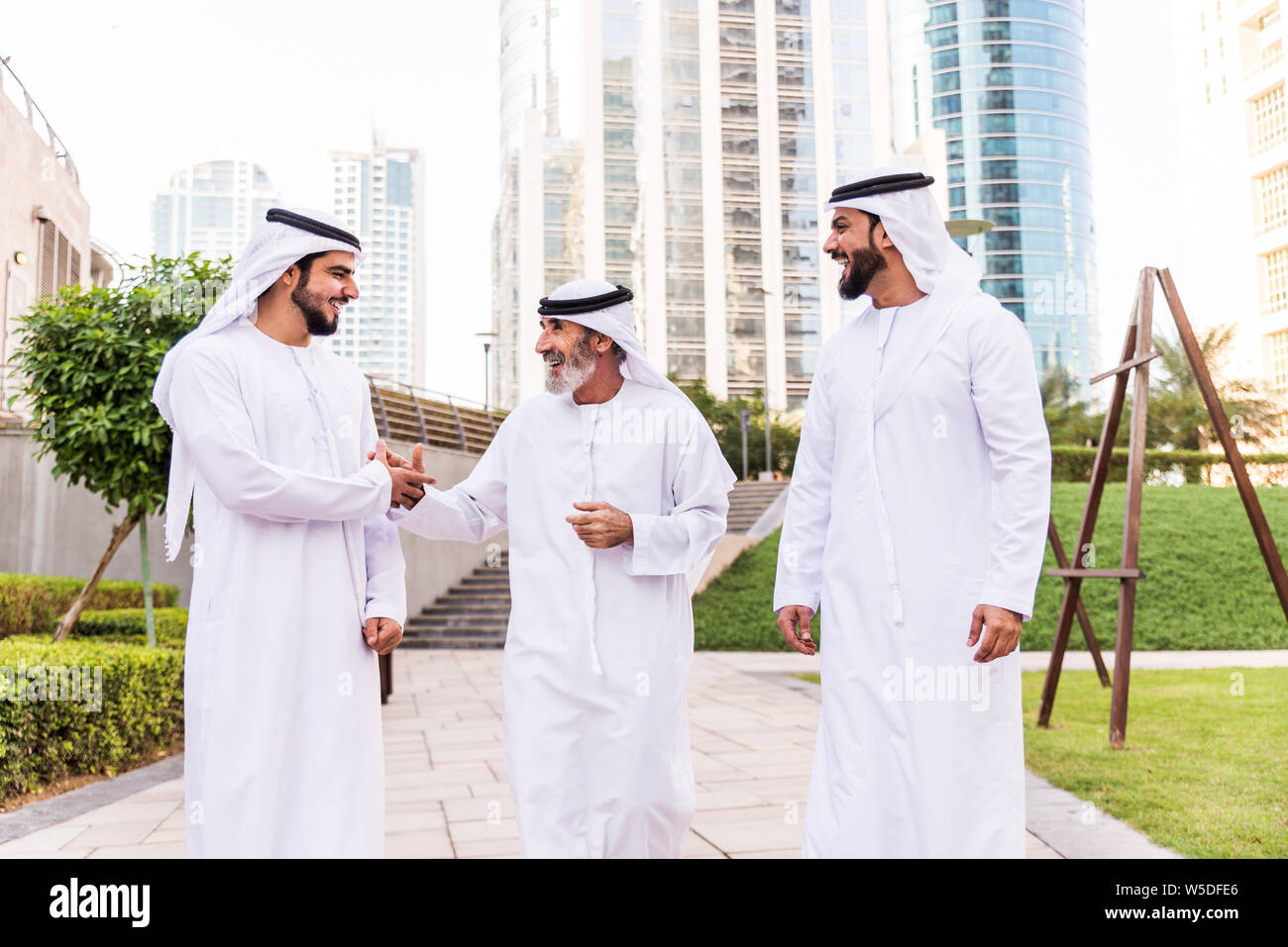 Three business men walking in Dubai wearing traditional emirati clothes ...