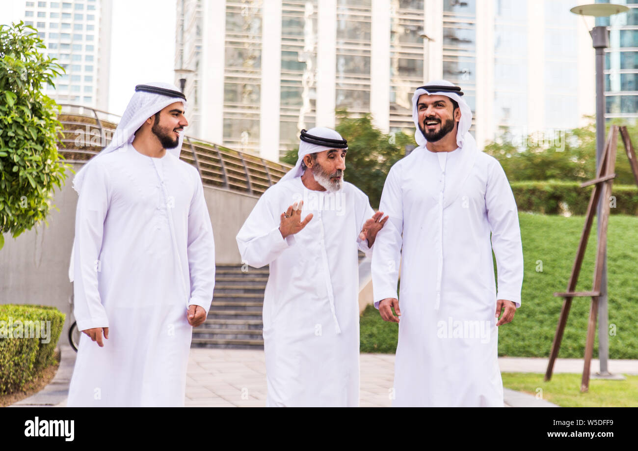 Three business men walking in Dubai wearing traditional emirati clothes ...