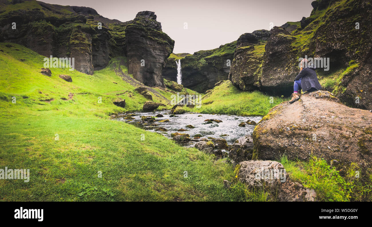 Woman sat looking at waterfall in Skógar Iceland Stock Photo