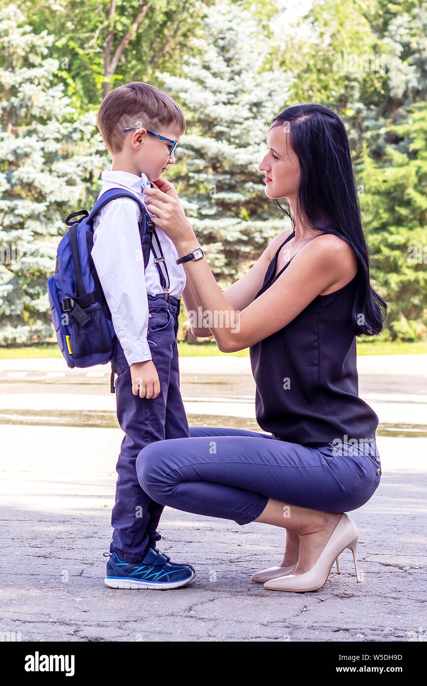 Young brunette mom escorts her first-grader's son to school. Back to school Stock Photo