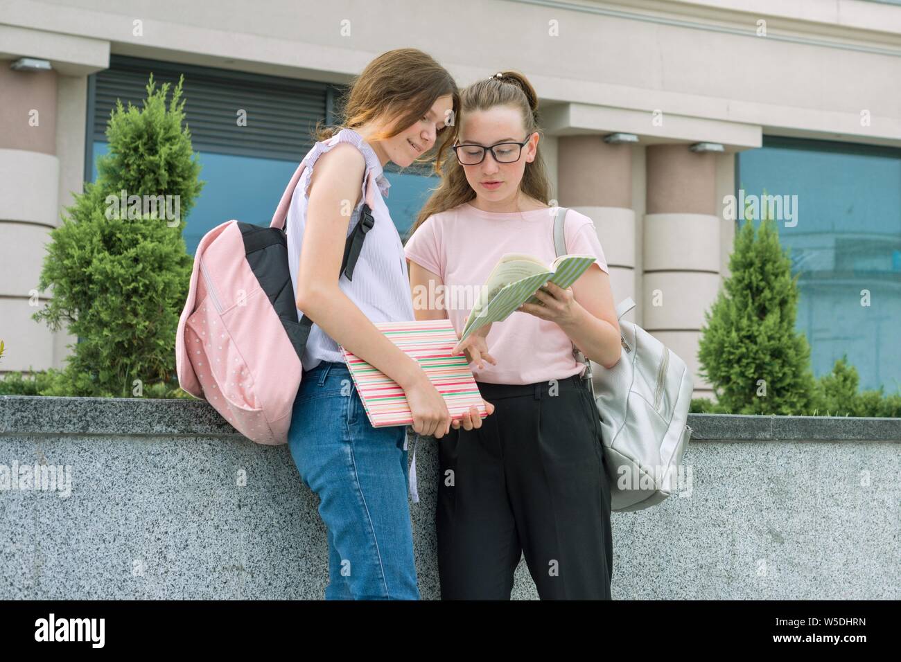 Outdoor portrait of two young beautiful girls students with backpacks ...
