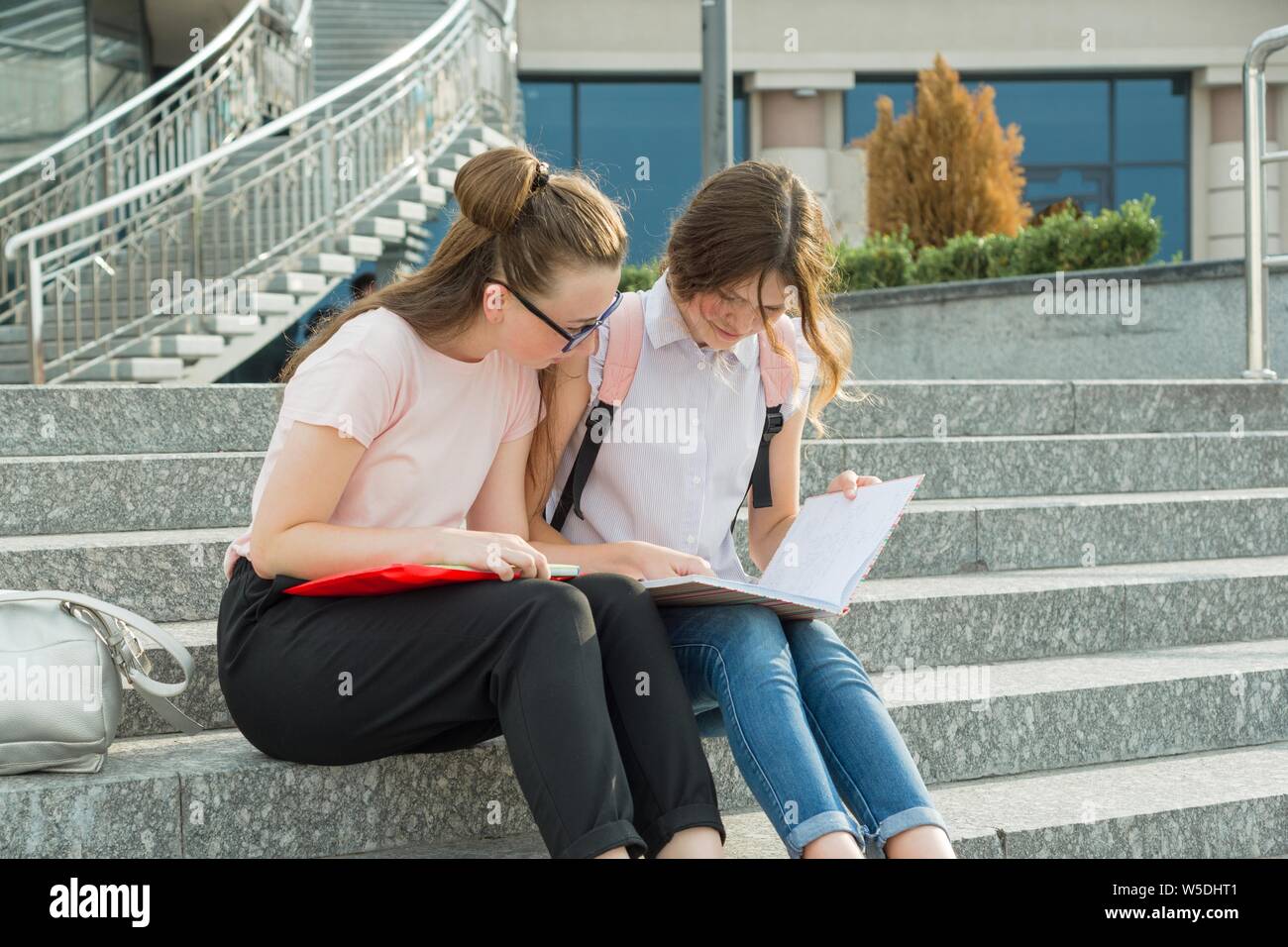 Outdoor portrait of two young beautiful girls students with backpacks ...