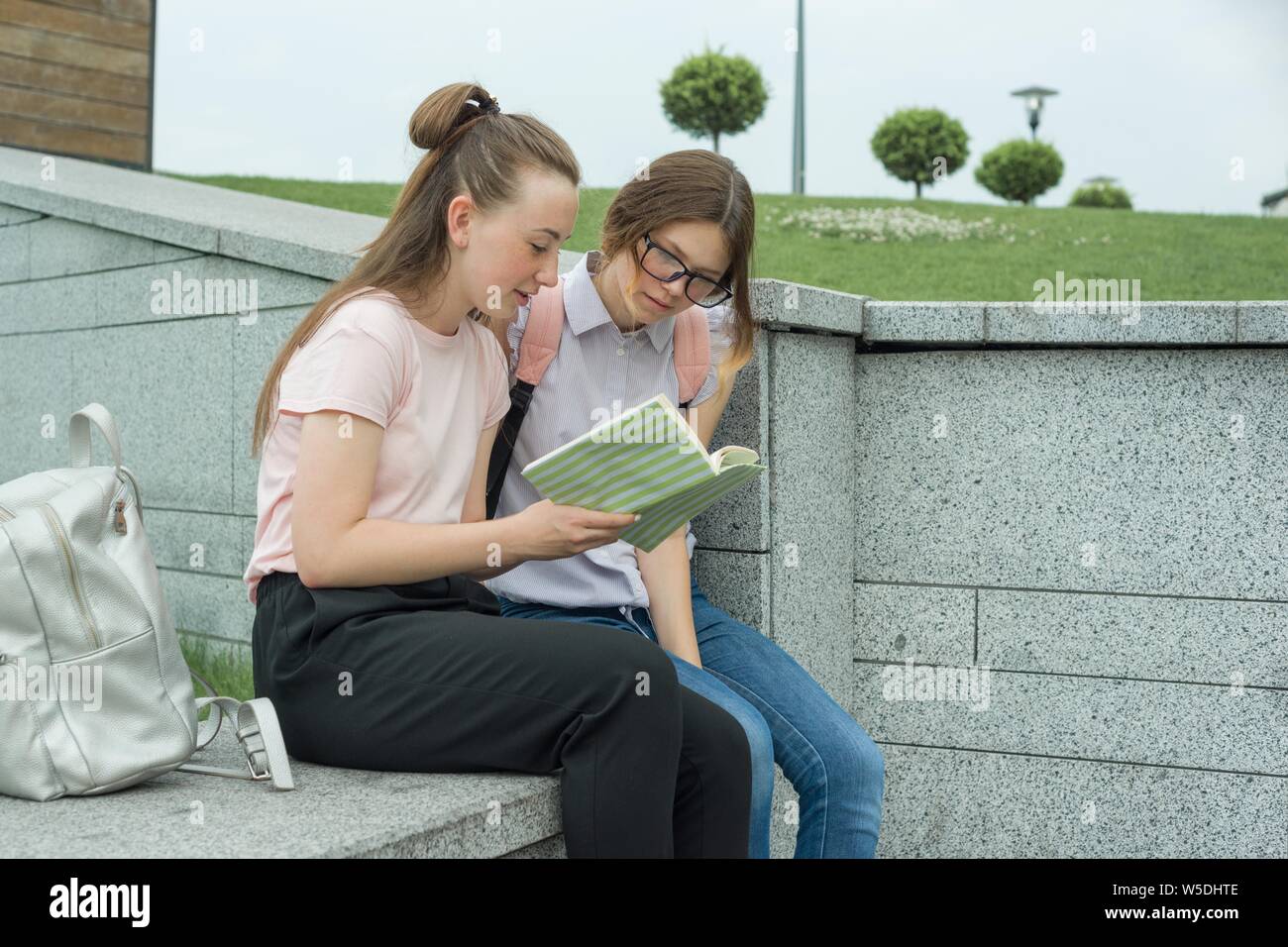 Outdoor portrait of two young beautiful girls students with backpacks ...