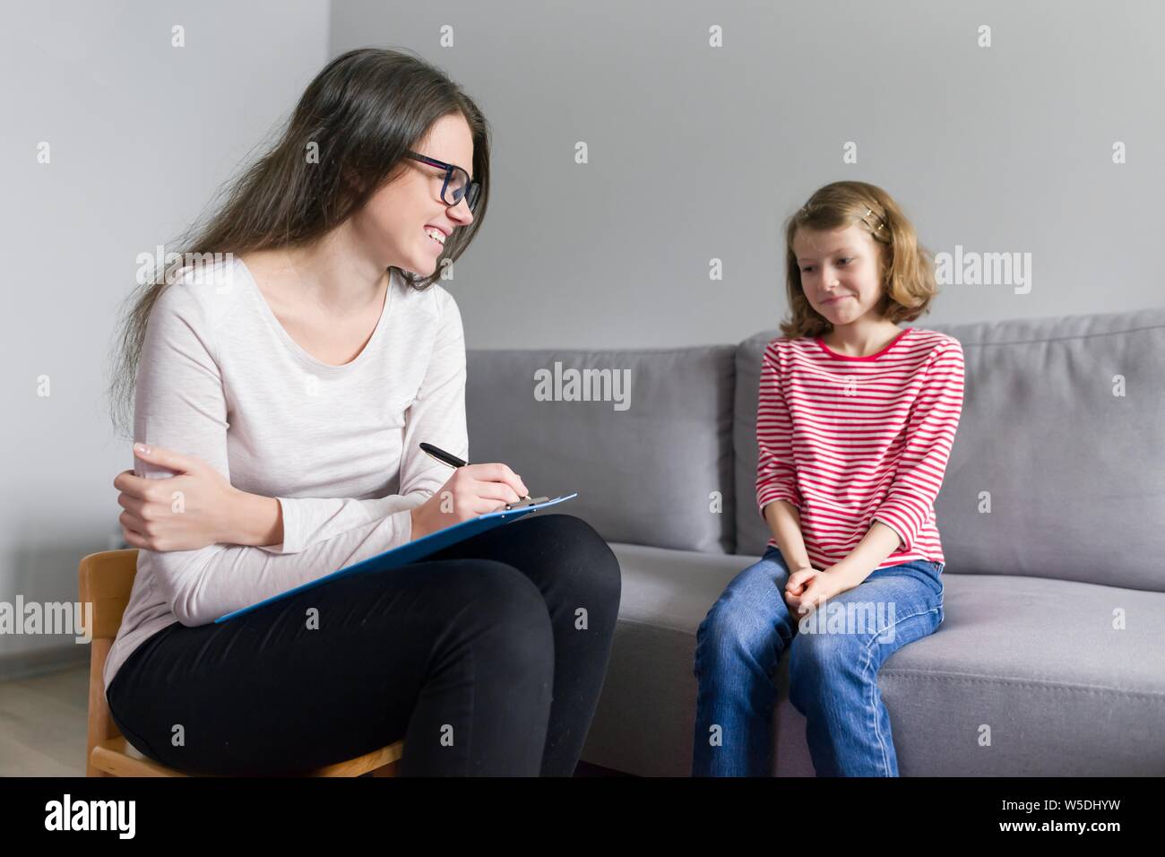 Professional child psychologist talking with child girl in office