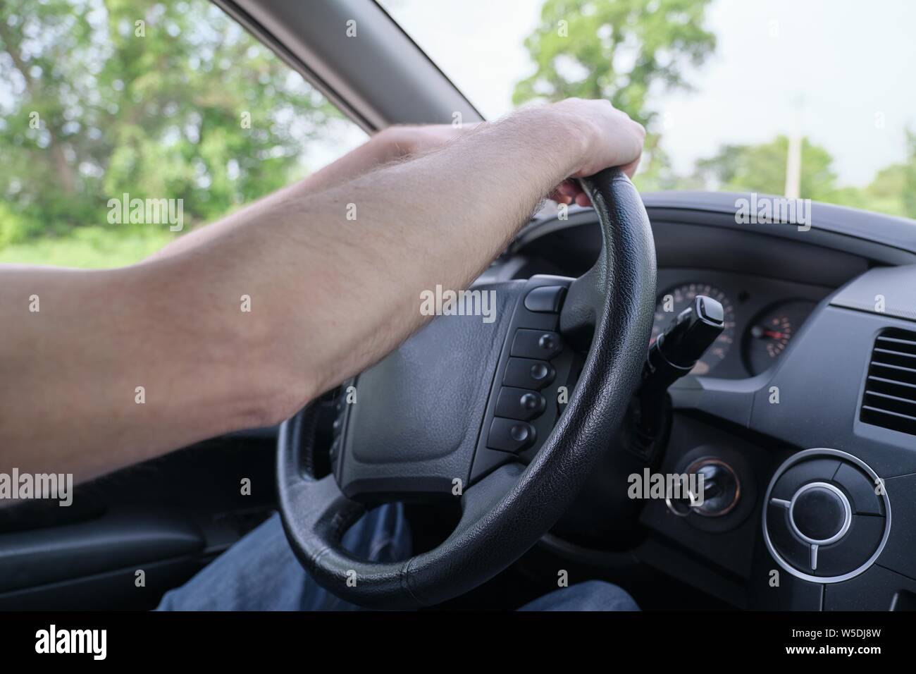 Drivers men hands on steering wheel, day time Stock Photo